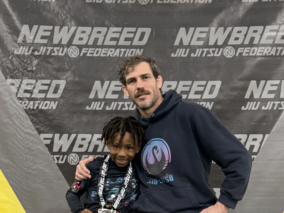Coach Clayton Phillips on the podium with one of his young athletes and their medal