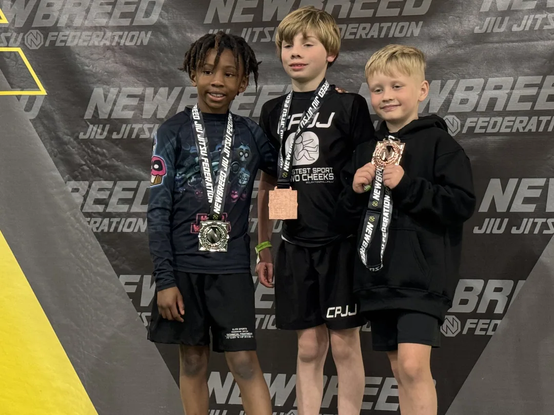 Three CPJJ kids on the podium with their medals at a Newbreed Jiu Jitsu Federation tournament