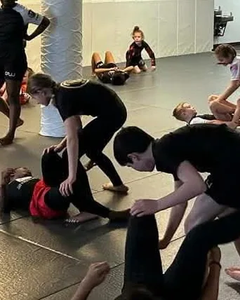 Kids drilling in pairs on the mats during a youth jiu jitsu class in Norfolk