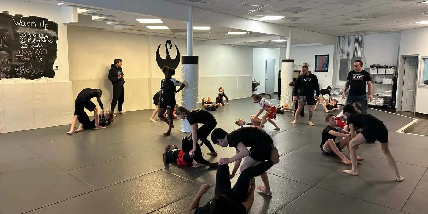 The CPJJ kids class drilling in pairs across the mats in Norfolk, with coaches working the room
